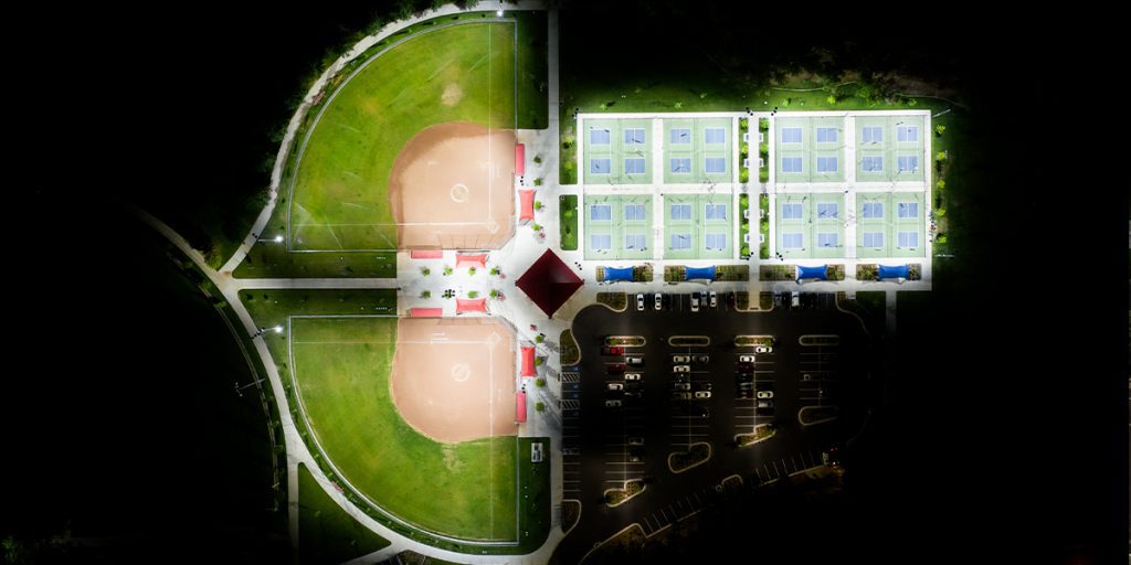 Overhead night view of the softball fields and pickleball courts at Spanish Fork Sports Complex. Fields and courts are lit with Musco TLC for LED system while surrounding areas remain dark