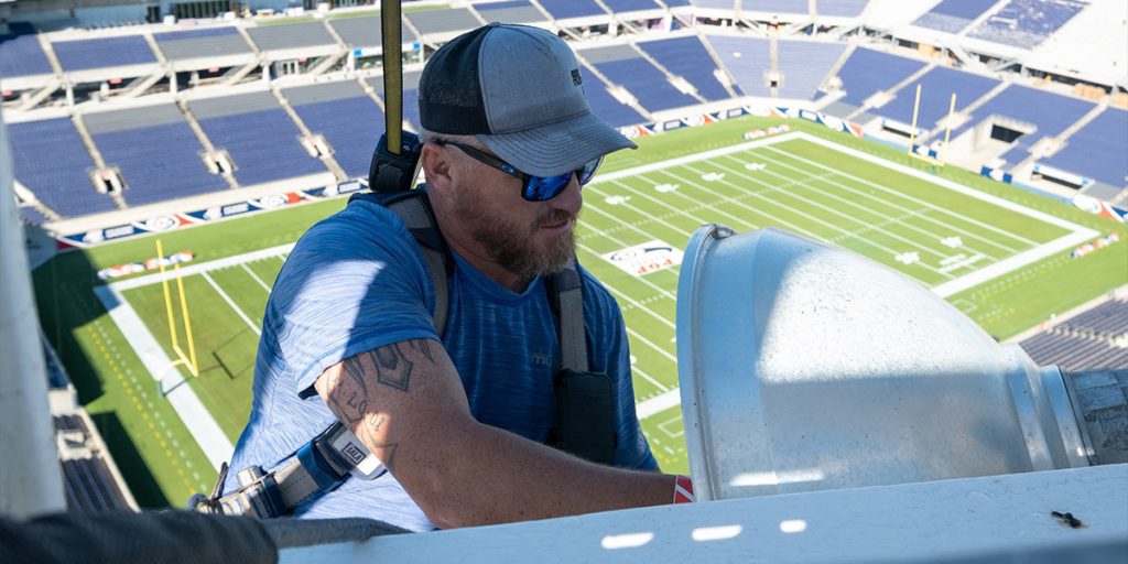 Musco technician installing stadium lighting above the Camping World Stadium field in Orlando Florida