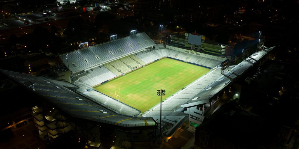 Football field at Bobby Dodd Stadium lit at night afte LED lighting upgrade with Atlanta, GA in the background