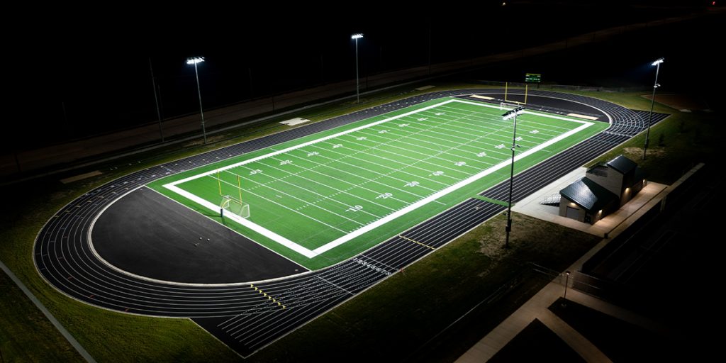 Night photo of the Jefferson High School football field surrounded by four light poles after LED sports lighting upgrade with Musco TLC for LED system