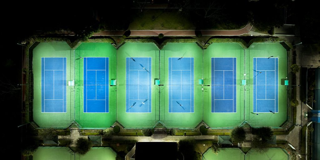 Overhead night view of the tennis courts at Club San Isidro. Factory aimed LED lighting fixtures light provide uniform lighting to playing surfaces while non-playing areas remain dark.