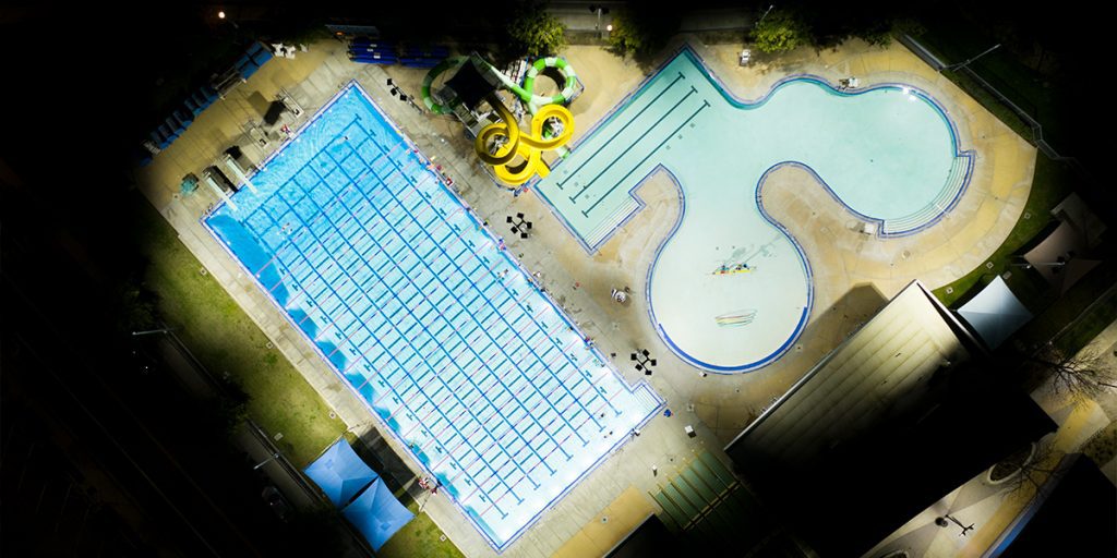 Overhead view of the McMurtrey Aquatic Center after LED lighting retrofit. The pools and recreational area are lit to optimal light levels while light spill and glare to surrounding areas is eliminated.