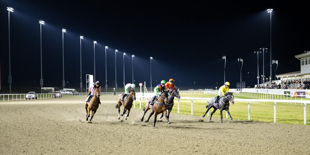 Horses run at Chelmsford City Racecourse with Musco factor-aimed LED lighting system in the background