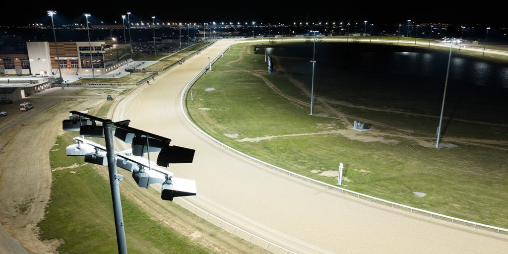 Musco TLC for LED fixture with horses racing at night on the track at Turfway Park in the background after the park upgrades to LED racecourse lighting.