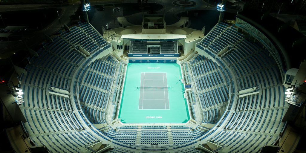 Championship tennis court at Zayed Sports City lit at night with increased light levels after tennis court lighting upgrade.