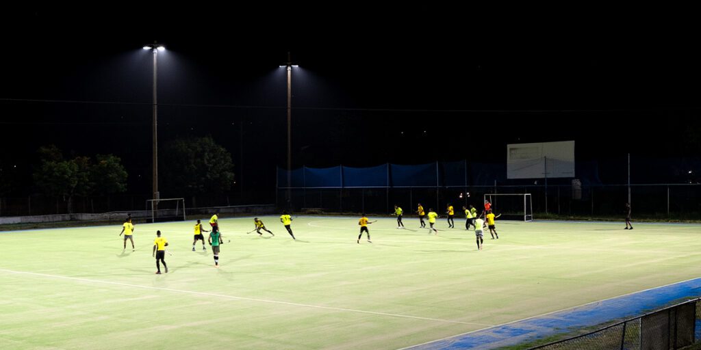 Athletes playing field hockey at night at the Jamaica Hockey Federation field with new LED sports lighting.
