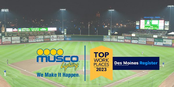 Musco Sports Lighting logo with We Make It Happen tagline and the Des Moines Register 2023 Top Work Places logo side by side with background image of a night game at Principal Park lit with Musco LED sports lighting poles and fixtures in the background