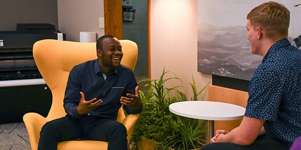 Two interns sit around a small white table sharing ideas at Musco Lighting.