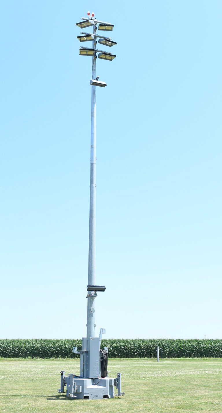 Musco's temporary Light-Structure system on portable base placed in a grass field with a cornfield and blue sky in the background.