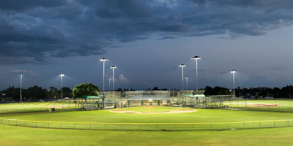 New Musco LED system lights baseball field at Pelican Park with cloudy sky in the background.