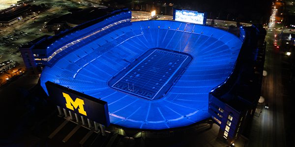 Overhead view of the football field and stands at Michigan Stadium lit in Michigan's azure blue.