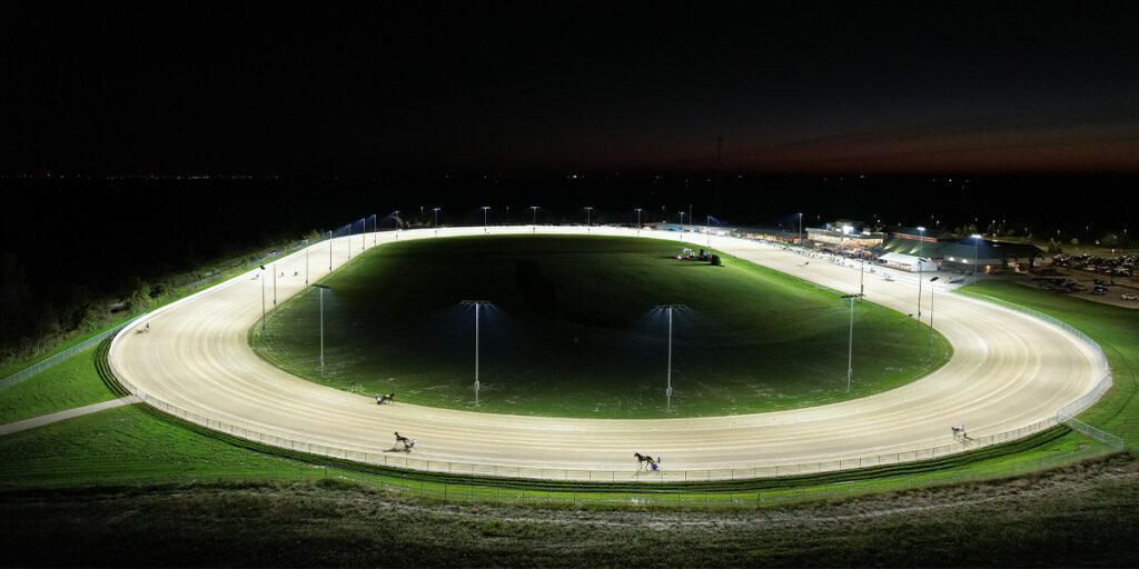 Grance River Raceway lit at night with horses on the track.