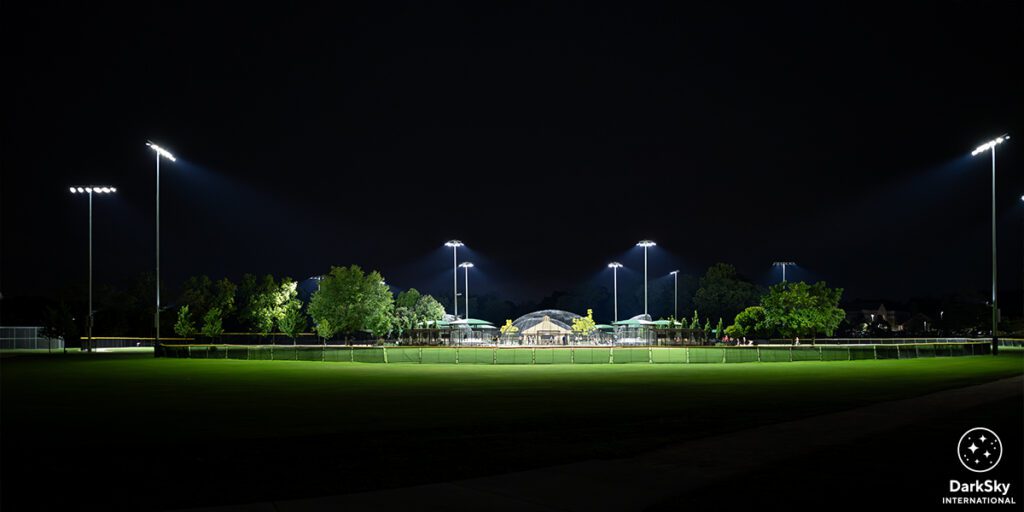 Baseball field at Glen Ellyn lit with new LED sports lighting fixtures. White DarkSky International logo in the bottom right corner.