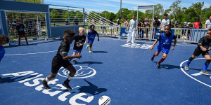Kids play soccer on a brand new mini-pitch with blue surface.